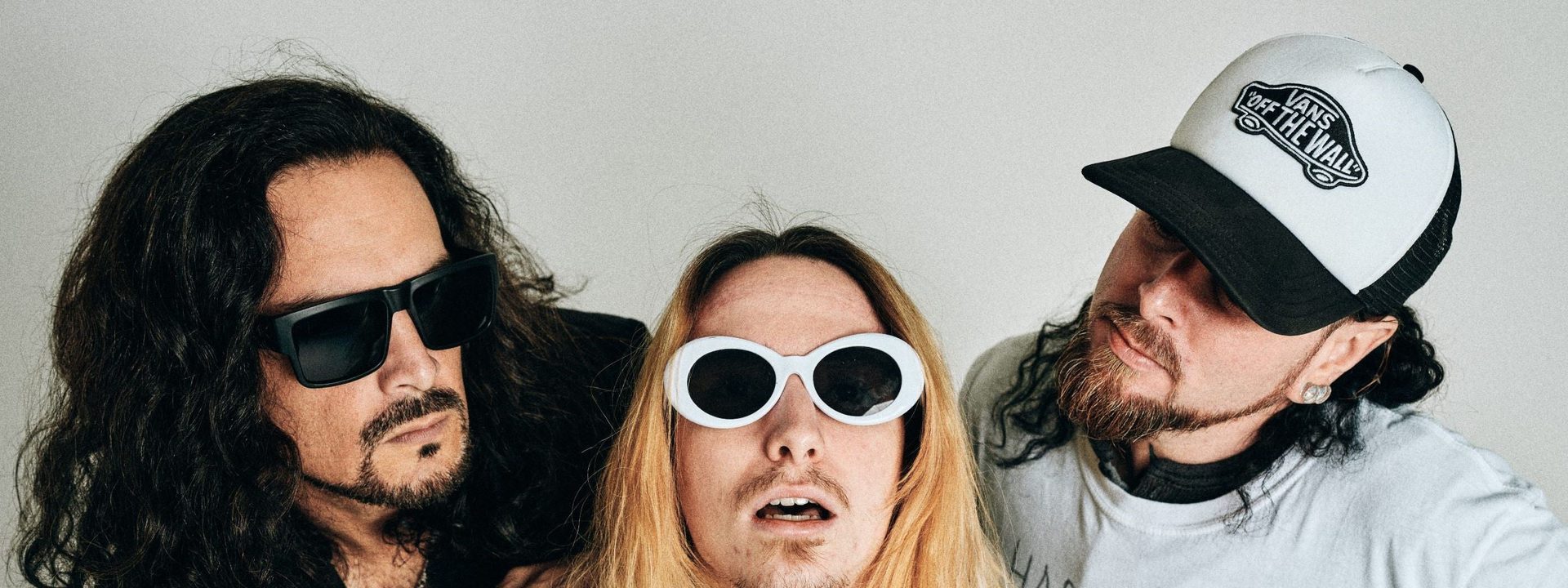 NIRVANNA [USA} - Tribute To Nirvana - Three musicians in 1990s-style clothing and sunglasses pose against a white background for NIRVANNA tribute band.