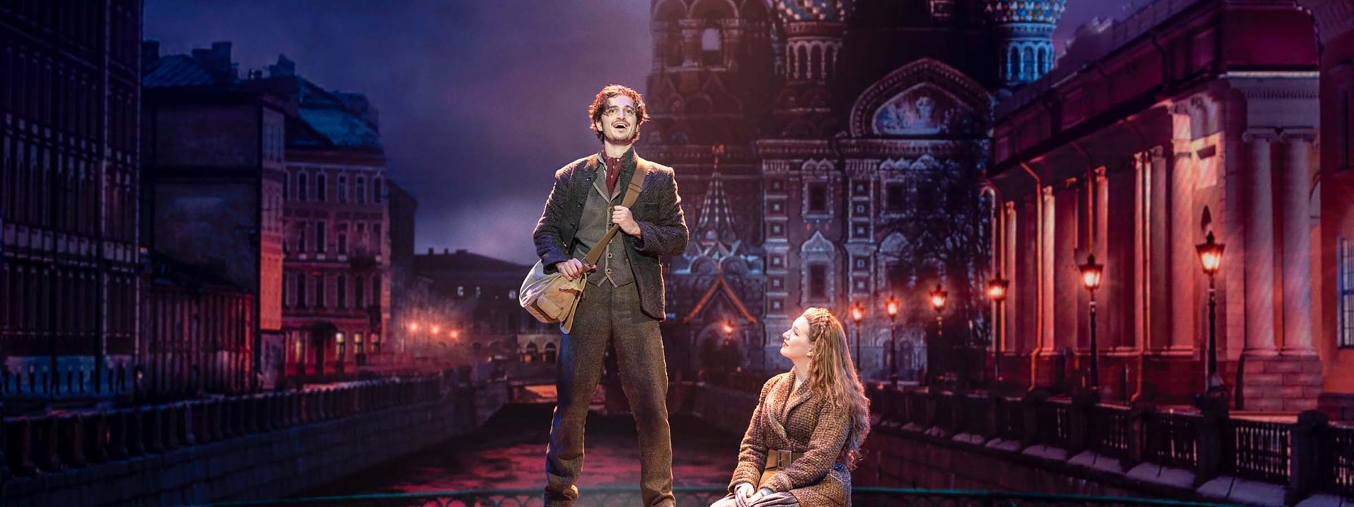 Anastasia the Musical sweeps into Adelaide with spectacle and heart - Two performers stand on a stage platform against an illuminated Russian cityscape backdrop in Anastasia the Musical.