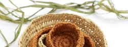Janelle’s Weaving - Woven basket in natural tan and brown tones arranged in a spiral spiral rose shape.