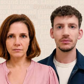 Woman in pink shirt and man in navy jacket face the camera against a neutral beige background.