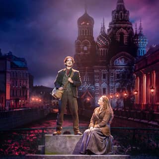 Anastasia the Musical sweeps into Adelaide with spectacle and heart - Two performers stand on a stage platform against an illuminated Russian cityscape backdrop in Anastasia the Musical.