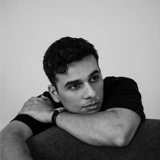 Anuv Jain - Dastakhat - World Tour 2026 - Man with dark hair resting head on folded arms against neutral background in black and white portrait.