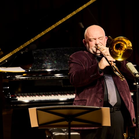 James Morrison Concert One | Brass Sonority - Musician plays trumpet while seated at piano during a brass sonority concert performance.