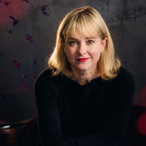 Hope Song Cycle (Presented by Jodie O'Regan) - Performer with blonde hair and red lipstick in black clothing against a dark red-lit background with bokeh effects.