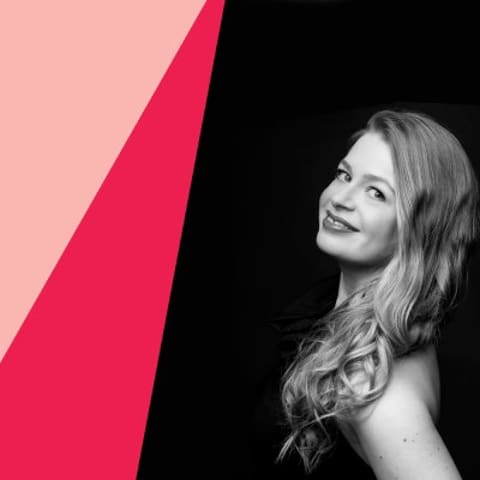 Chamberfest Concert Three | Kurtág 100 – Kafka Fragments - Woman with long hair smiling against a pink and black geometric background.