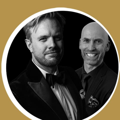 Love & Loss (Presented by State Opera South Australia) - Two men in formal attire smile at the camera in a circular black and white portrait against a gold background.