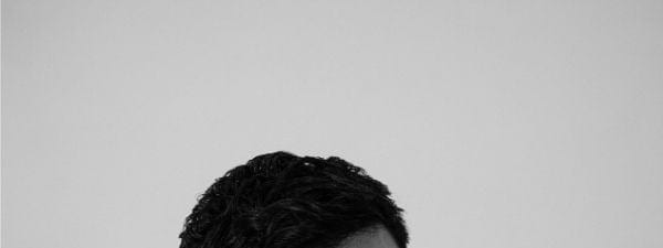 Anuv Jain - Dastakhat - World Tour 2026 - Man with dark hair resting head on folded arms against neutral background in black and white portrait.