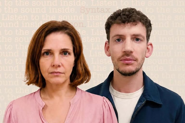 Woman in pink shirt and man in navy jacket face the camera against a neutral beige background.