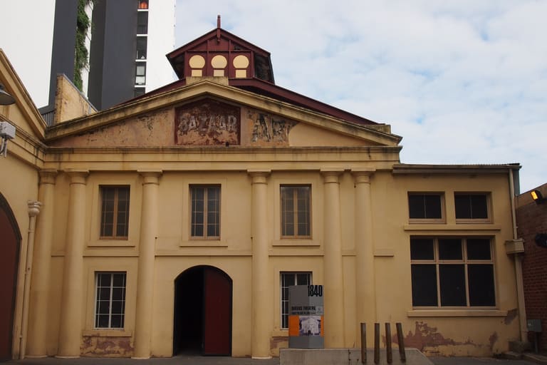 The Queens Theatre - Historic cream-coloured building with columned facade, domed roof cupola, and arched entrance doorway.
