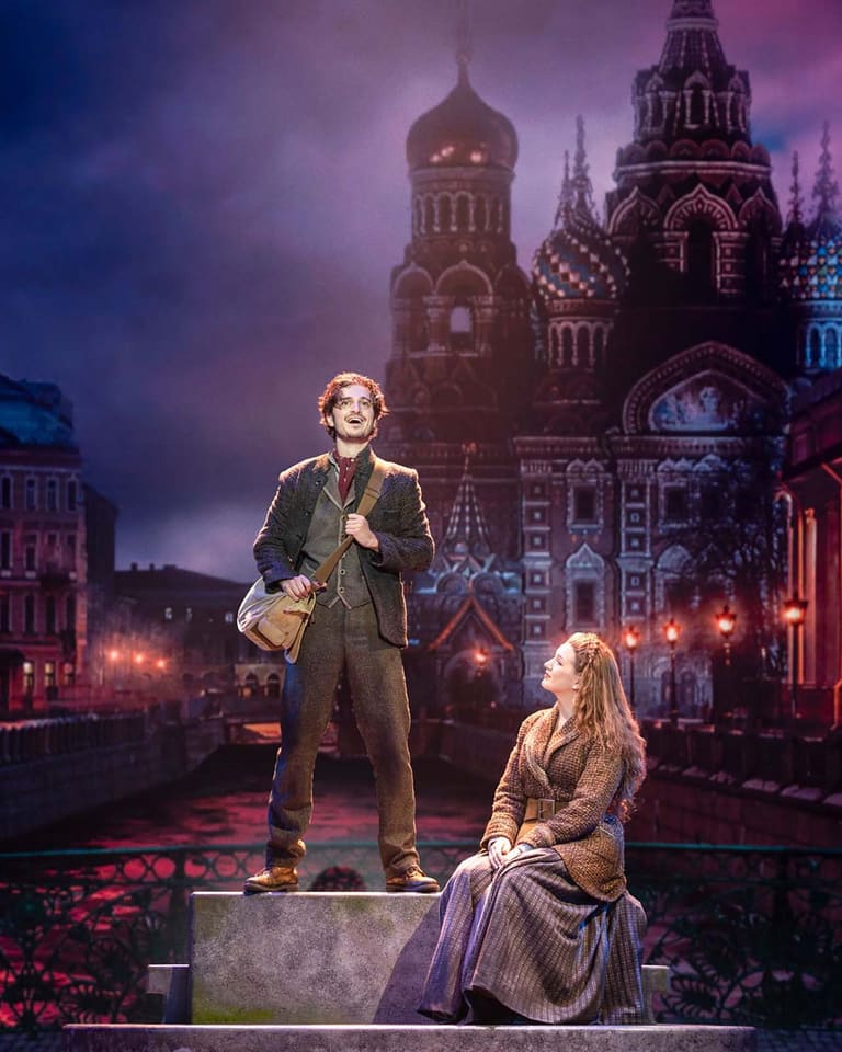 Anastasia the Musical sweeps into Adelaide with spectacle and heart - Two performers stand on a stage platform against an illuminated Russian cityscape backdrop in Anastasia the Musical.