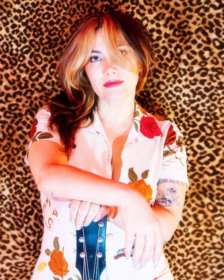 Person with reddish hair in a patterned shirt against a leopard print backdrop, gazing upward.