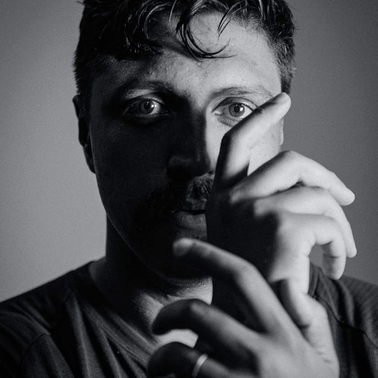 Person with hand covering half their face in black and white portrait photography.