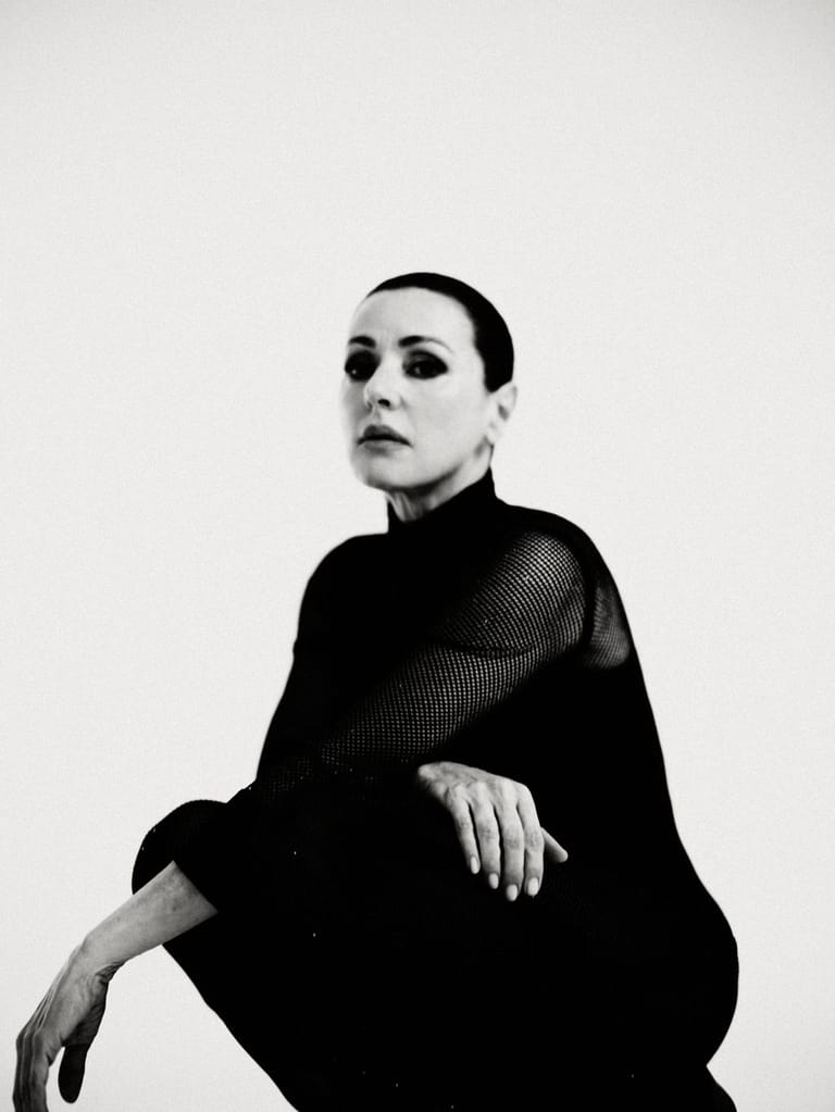 Person in black turtleneck gazes upward against a neutral white background in black-and-white portrait photography.