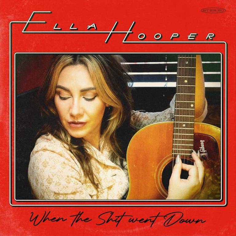 Woman with long brown hair holding an acoustic guitar against a red background with album text.