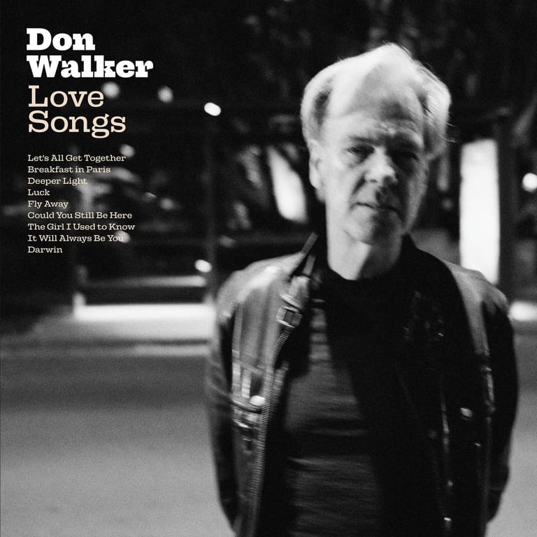 Man in dark jacket stands outdoors at night in black and white photograph for "Love Songs" album cover.