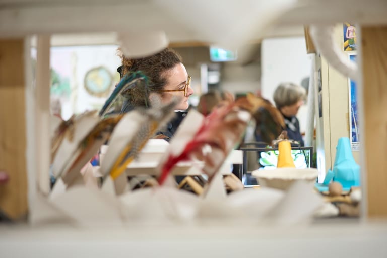 Man in glasses holds a kookaburra indoors with other birds perched nearby.