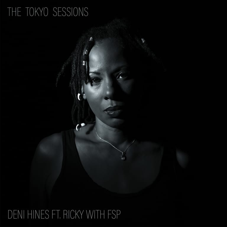 Musician wearing headphones illuminated against a black background, promotional image for new music single.