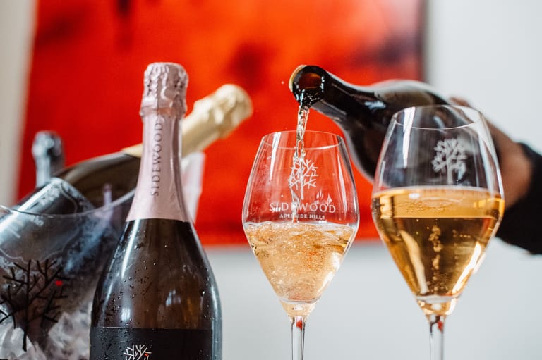 Champagne bottle and glasses filled with sparkling wine against a warm red and orange blurred background.