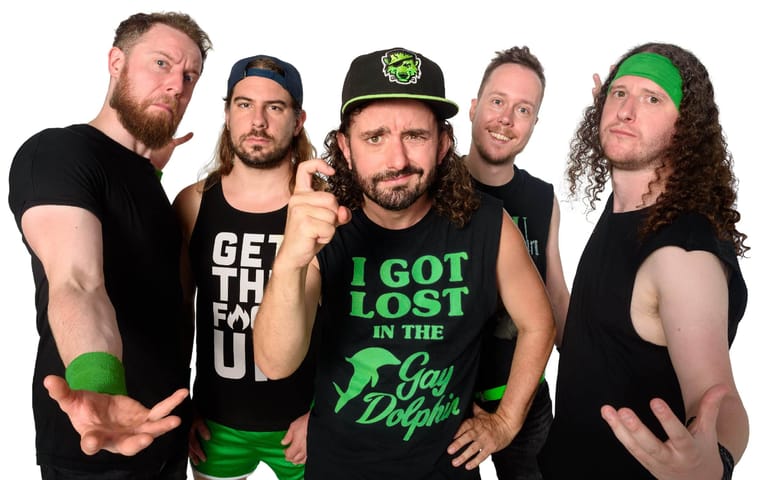 Five band members in black and green clothing pose together against a dark background.
