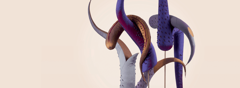 Two acrobats suspended mid-air in coordinated poses, draped in flowing purple and burgundy fabric against a neutral background.