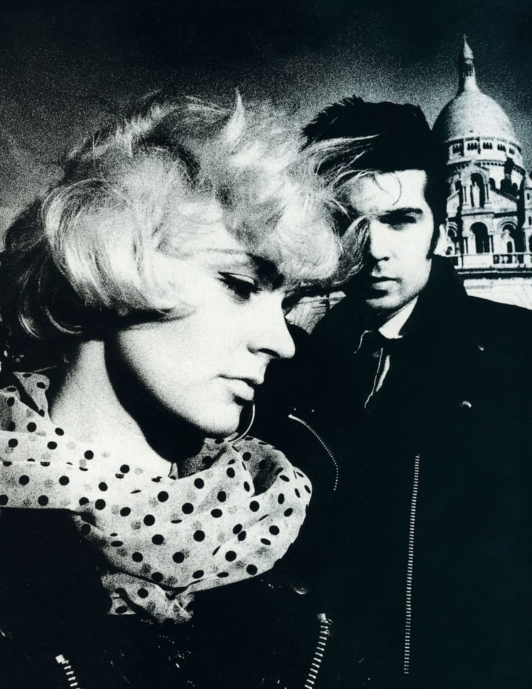 Two figures in profile against a Parisian backdrop in a black and white film still.