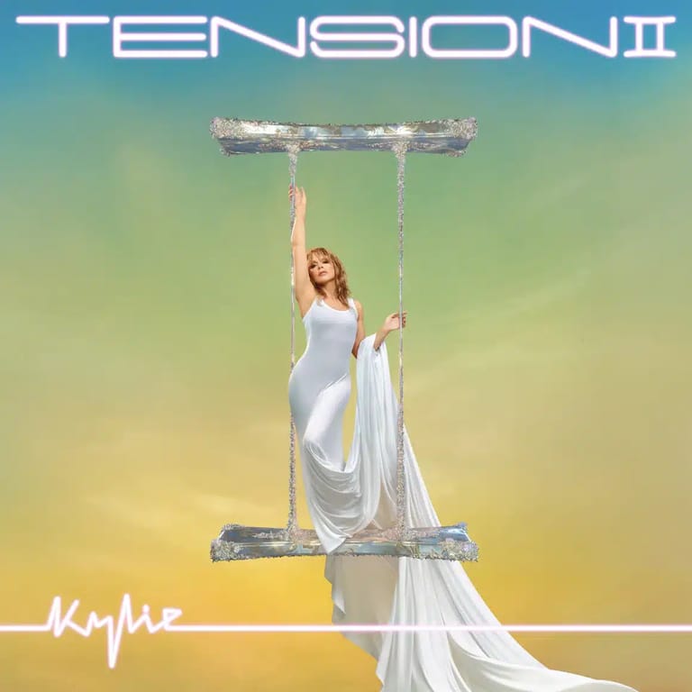 Performer in white fabric suspended from horizontal bar against gradient yellow-green sky on album cover.