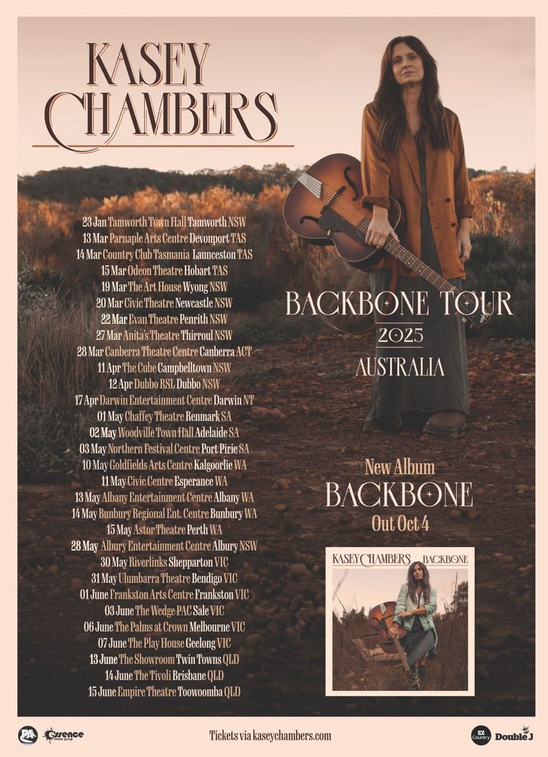 Kasey Chambers stands holding a guitar in an autumn field, promoting her 2025 Backbone Tour across Australian venues.