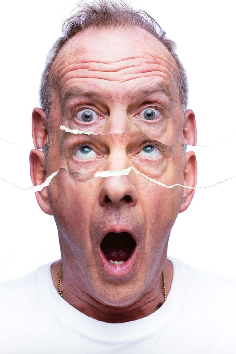 Man with exaggerated shocked expression wearing four pairs of eyes cut from paper on his face against white background.
