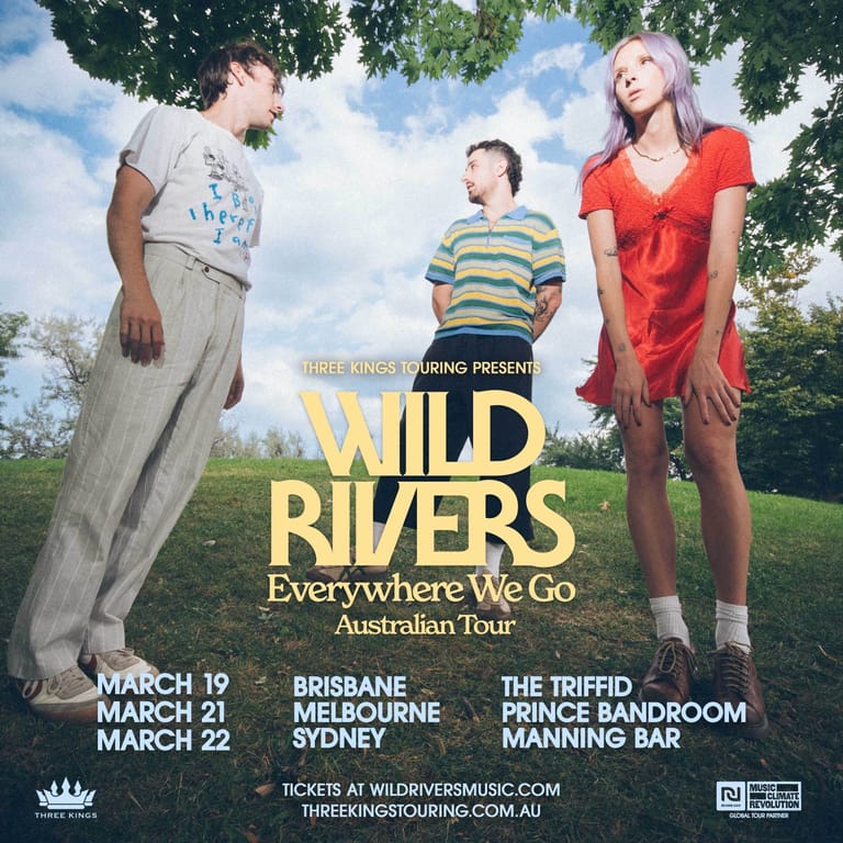 Three young people pose outdoors under tree foliage promoting Wild Rivers' "Everywhere We Go" Australian tour.