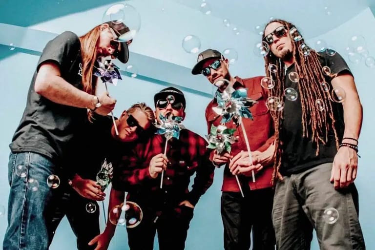 Band members in festive attire perform together against a bright blue backdrop with falling snow effects.