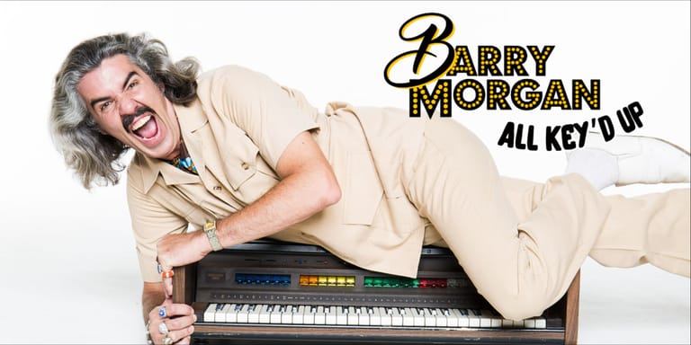 Man in cream suit draped across a keyboard, grinning at camera with "Barry Morgan All Keyed Up" text overlay.