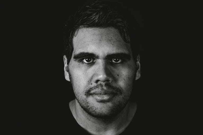 Monochrome portrait of a man with dark hair against a black background.