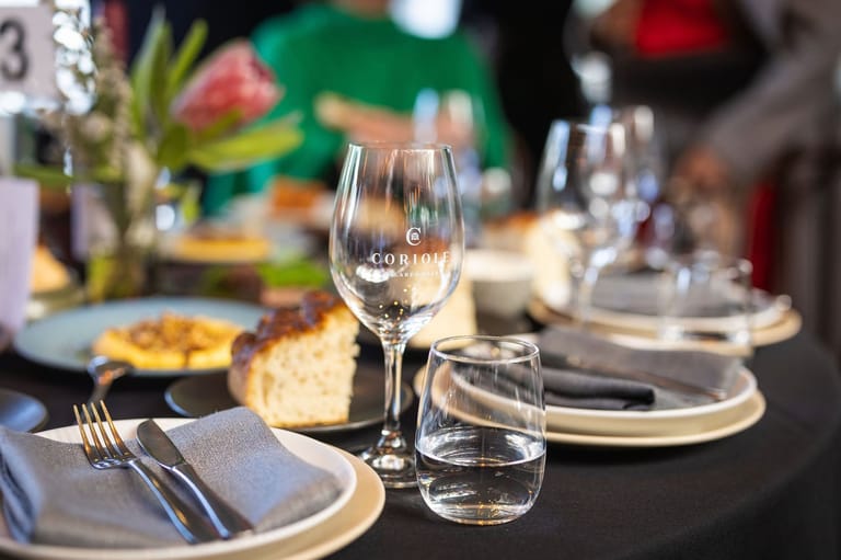 Elegant table setting with wine glasses, place settings and colourful floral centrepiece at a formal dinner event.