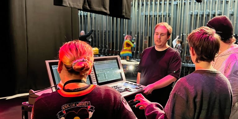 Musicians and sound engineers collaborate at a recording studio setup with laptops and mixing equipment.