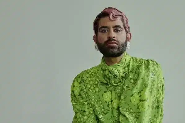 Person with pink-tinted hair wearing a bright lime-green patterned shirt against a neutral background.