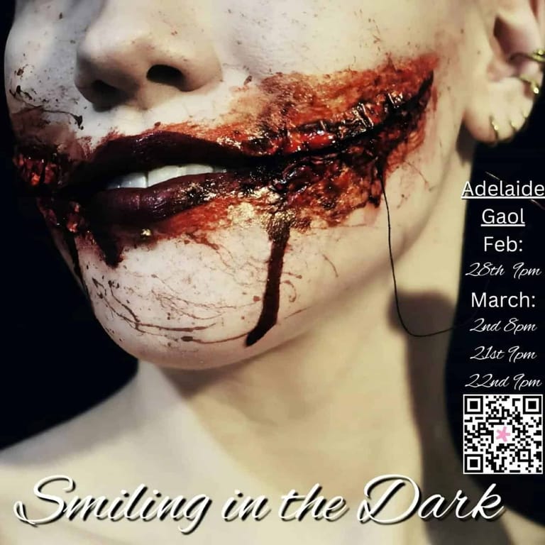 Close-up of a pale face with theatrical blood makeup and a sinister expression against dark lighting.