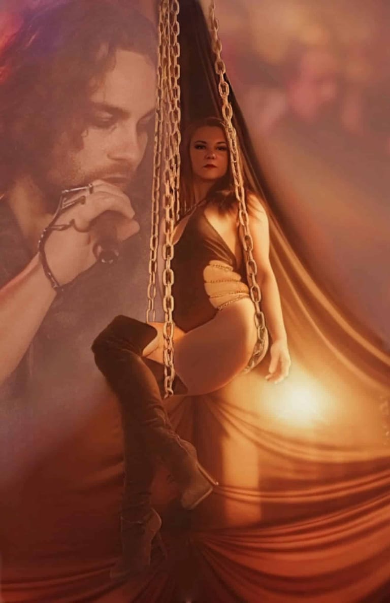 Performer draped in golden fabric and chains against warm-toned lighting with projected imagery overlay.