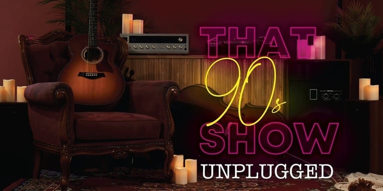 Acoustic guitar and burgundy armchair beside neon signage reading "THAT 90s SHOW UNPLUGGED" with warm candlelit ambiance.