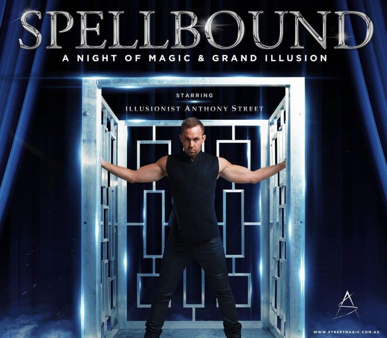 Illusionist Anthony Street stands with arms outstretched inside an illuminated geometric doorway for the Spellbound stage production.