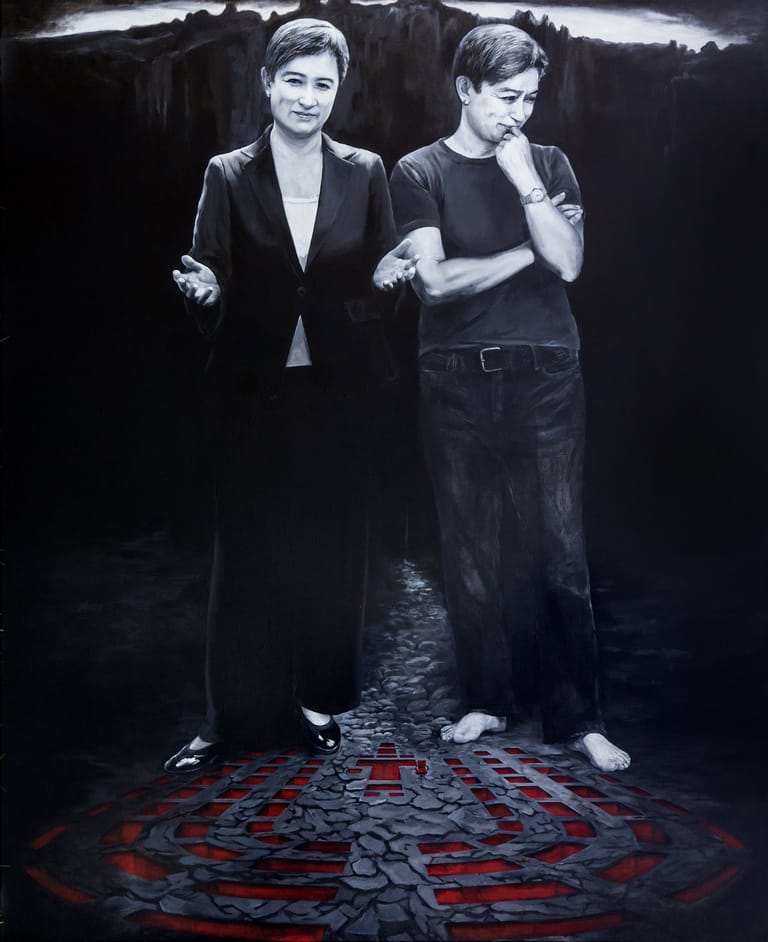 Two performers stand on a geometric red and grey patterned floor against a dark atmospheric backdrop.