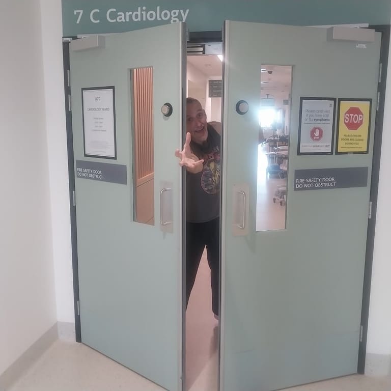 Person entering a medical clinic doorway marked "7 C Cardiology" in a hospital corridor.