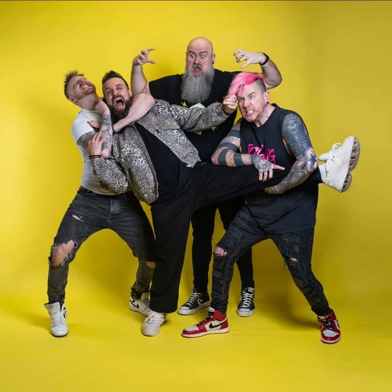 Five men in casual attire strike an exuberant pose against a bright yellow background.