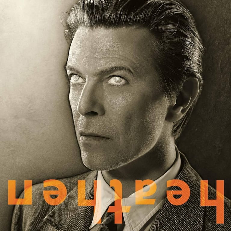Black and white portrait of a man with swept-back dark hair against a neutral background, with orange reversed text overlay.