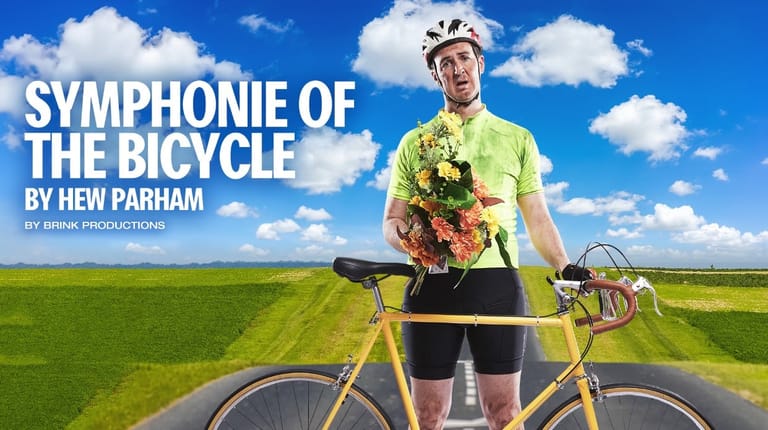 Cyclist in yellow and black kit holding flowers stands with bicycle in vast green field under blue sky.