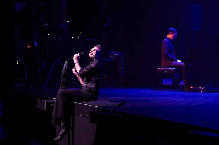 Two performers on stage bathed in blue spotlights during a theatrical production.