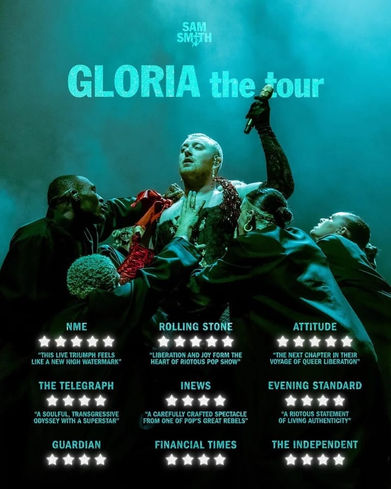 Performer in red jacket surrounded by actors in dramatic turquoise lighting during a theatrical production of Gloria the Tour.