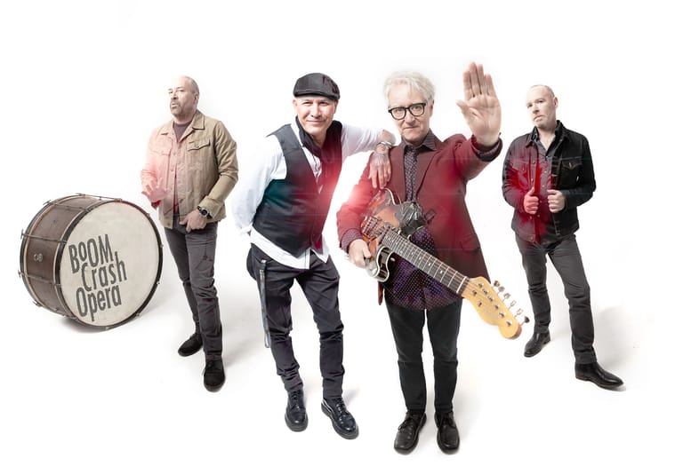 Five musicians pose together with a bass drum labelled "South Australian Opera" beside them.
