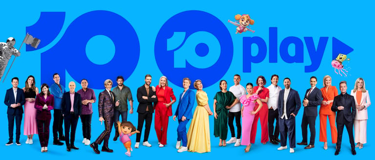 Large group of people in formal and colourful attire standing together against a bright blue background with "play" branding.