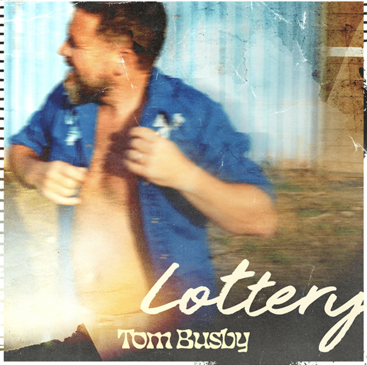 Man in blue shirt gesturing expressively against ethereal blue-tinted backdrop, album cover for "Lottery" by Tom Busby.