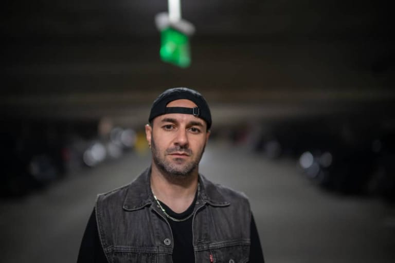 Man in denim jacket and headband standing beneath green traffic light.